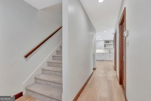 stairway with baseboards, wood finished floors, and recessed lighting