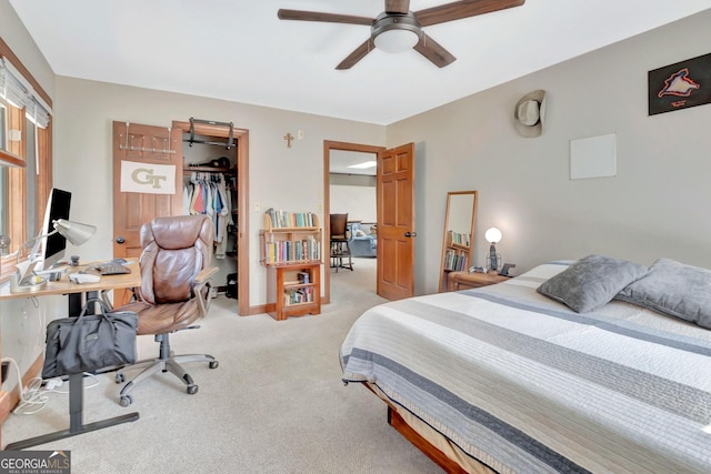 bedroom featuring a ceiling fan, a walk in closet, a closet, and light colored carpet