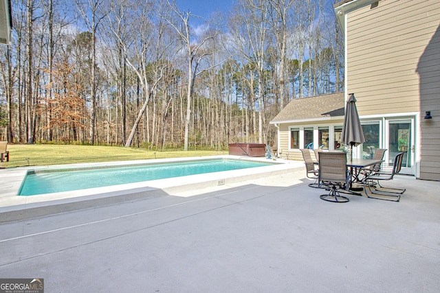 pool with a patio, a yard, and a hot tub