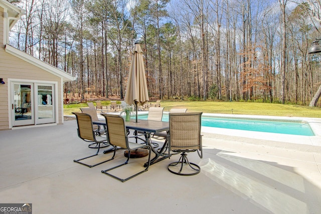 pool featuring a patio, outdoor dining area, and a lawn