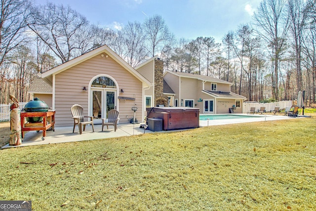 back of property with a yard, a hot tub, a patio area, fence, and a swimming pool