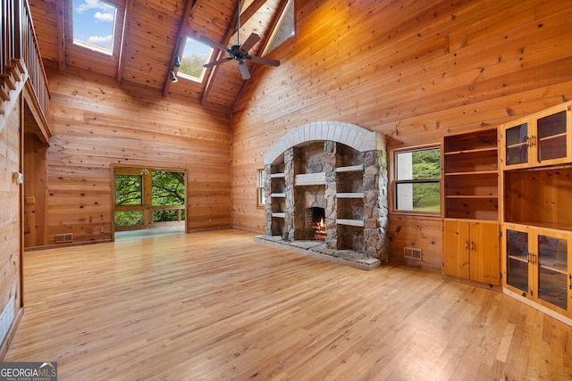 unfurnished living room featuring visible vents, a fireplace, wooden walls, and wood finished floors