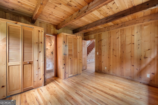 unfurnished bedroom with wooden ceiling, light wood-style flooring, wooden walls, and beam ceiling