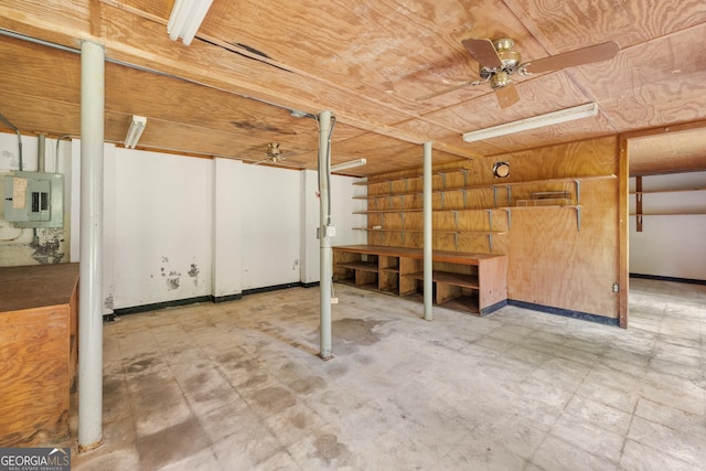 below grade area with ceiling fan, baseboards, electric panel, and tile patterned floors