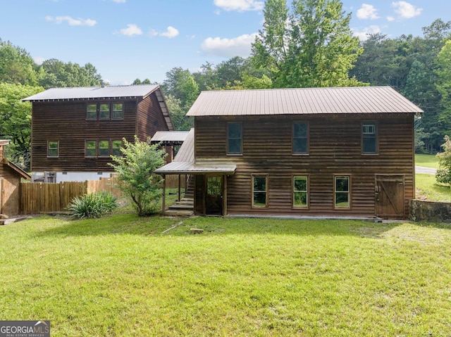 back of house featuring metal roof, a yard, and fence