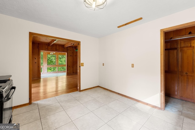 interior space with wood walls, baseboards, a textured ceiling, and light tile patterned flooring