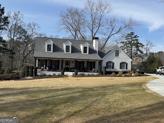 cape cod house with a porch, a front yard, roof with shingles, and a chimney