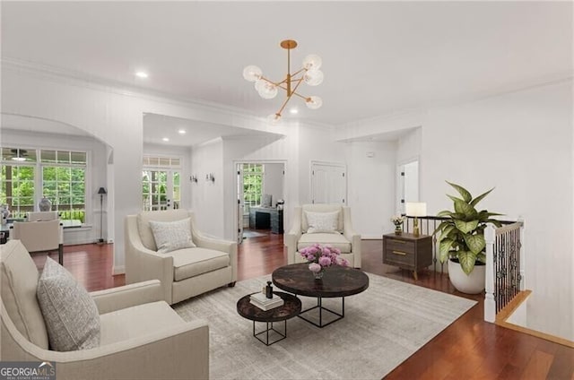 living area with baseboards, wood finished floors, crown molding, a notable chandelier, and recessed lighting