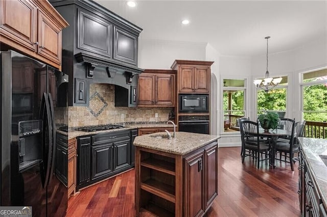 kitchen featuring a notable chandelier, a sink, backsplash, a wealth of natural light, and black appliances