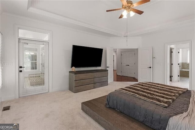 bedroom with a tray ceiling, carpet, crown molding, visible vents, and a ceiling fan