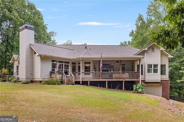 rear view of property with a yard, a chimney, a ceiling fan, a deck, and a garage