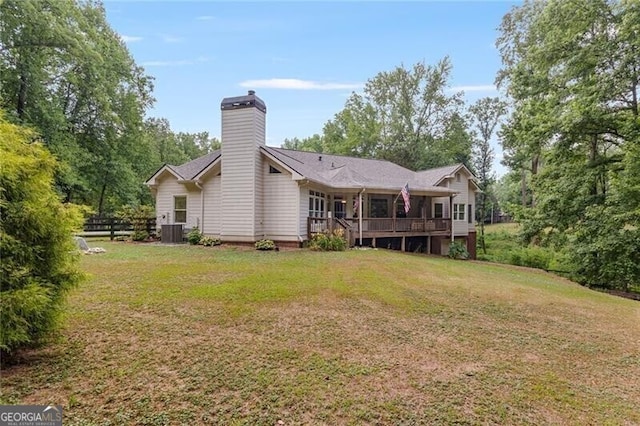 back of house featuring cooling unit, a chimney, a lawn, and a deck