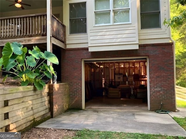 doorway to property with ceiling fan, brick siding, and an attached garage