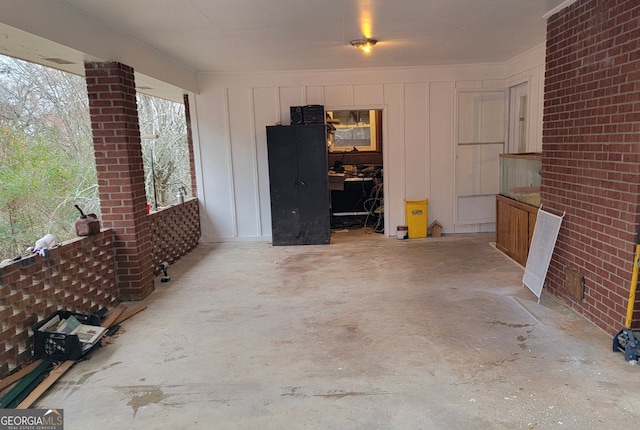 interior space with brick wall and unfinished concrete flooring