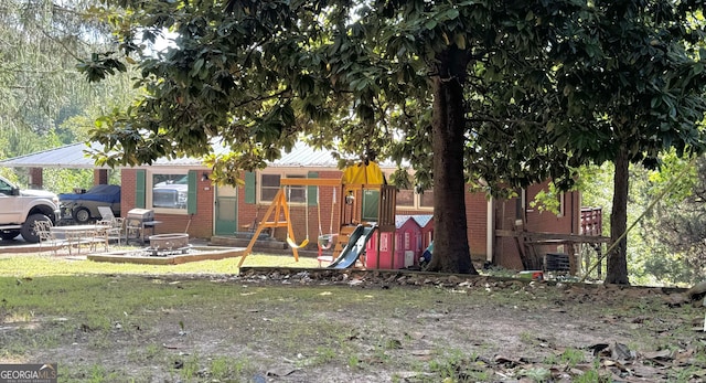 view of jungle gym featuring an outdoor fire pit, a patio area, and a lawn