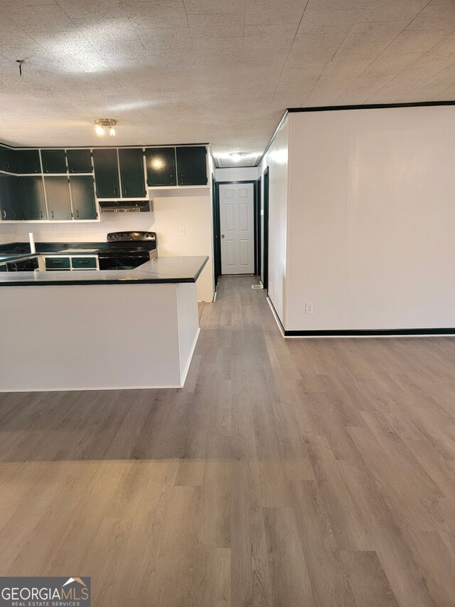 kitchen with dark countertops, stove, a sink, dishwasher, and a peninsula