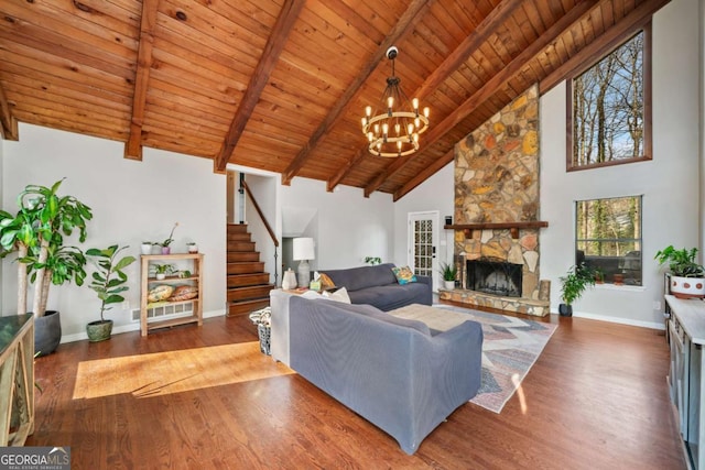 living room featuring a stone fireplace, wooden ceiling, wood finished floors, baseboards, and stairs