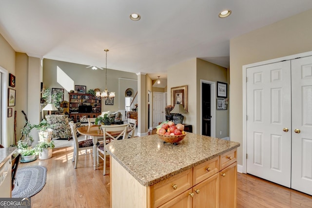 1301 Dayspring Trce, Lawrenceville, GA 30045 - kitchen featuring a chandelier, light stone counters, light wood-type flooring, and a center island