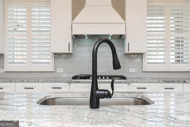 kitchen featuring tasteful backsplash, white cabinetry, and custom exhaust hood