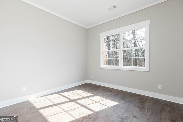 unfurnished room featuring baseboards, visible vents, wood finished floors, and ornamental molding