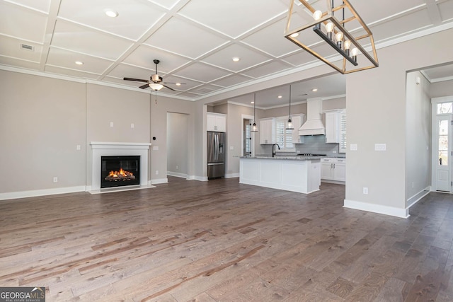 unfurnished living room featuring dark wood-style flooring, coffered ceiling, ceiling fan, and baseboards