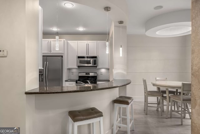 kitchen with appliances with stainless steel finishes, a breakfast bar area, backsplash, and dark stone countertops