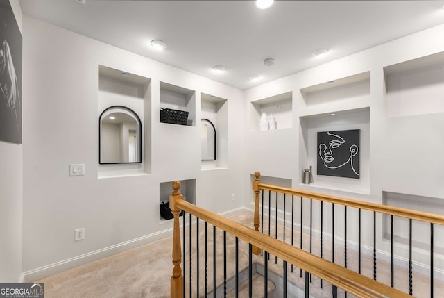 hallway with baseboards, carpet, and an upstairs landing
