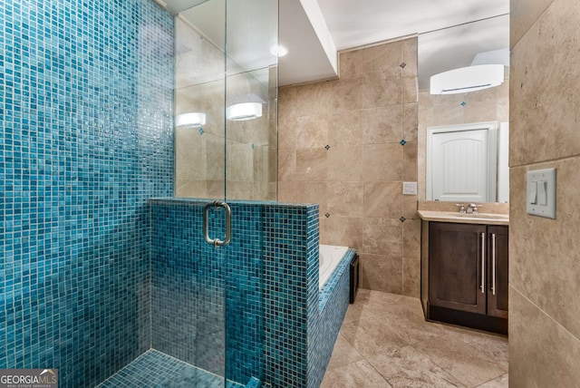 bathroom with tiled bath, vanity, tile patterned floors, tile walls, and a stall shower