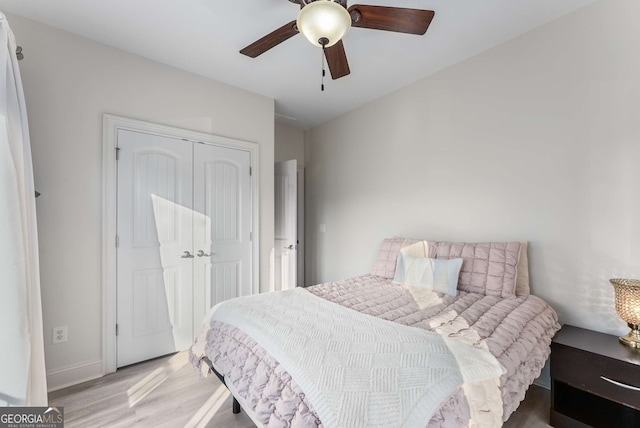 bedroom with light wood-style floors, a ceiling fan, baseboards, and a closet