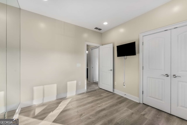 unfurnished bedroom with recessed lighting, a closet, visible vents, wood finished floors, and baseboards