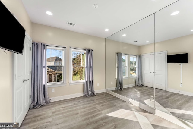 unfurnished bedroom featuring recessed lighting, baseboards, multiple windows, and light wood-type flooring