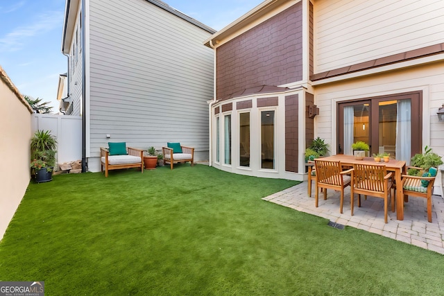 rear view of property featuring fence, a patio, and a lawn