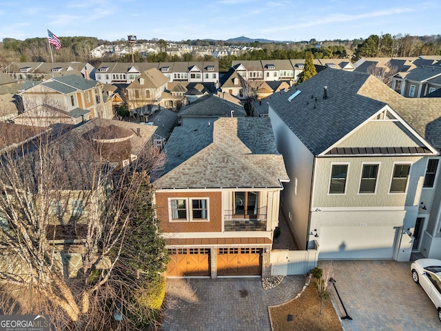 view of front of home featuring a garage, decorative driveway, roof with shingles, and a residential view
