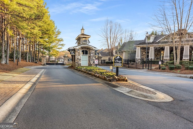 view of road with curbs, a gated entry, sidewalks, and a gate