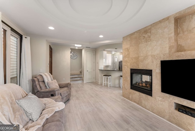 living area with recessed lighting, a fireplace, stairs, and light wood-style flooring