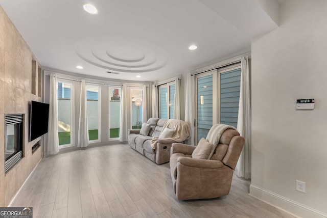 living room featuring a fireplace, recessed lighting, baseboards, and light wood-style floors