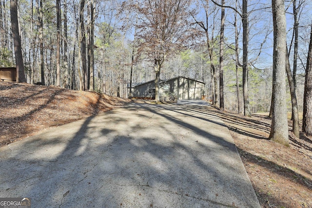 view of road featuring driveway and a view of trees