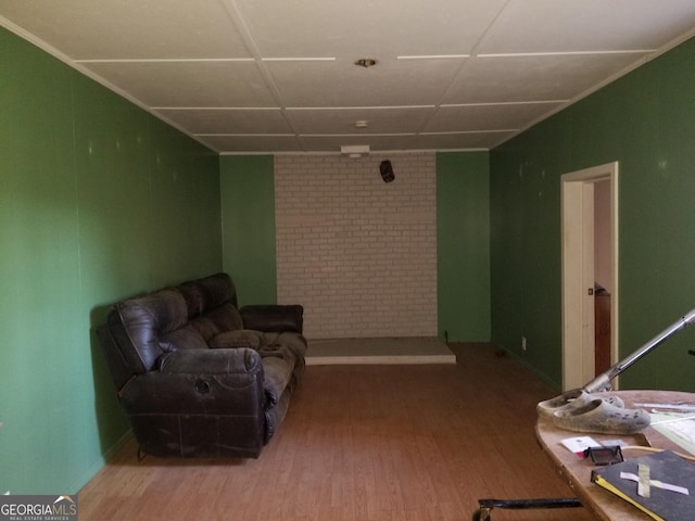 living area with brick wall and wood finished floors