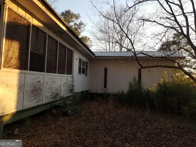 view of property exterior with metal roof and a sunroom