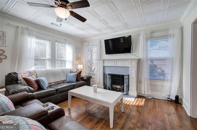 living area with a wealth of natural light, a fireplace, wood-type flooring, and an ornate ceiling