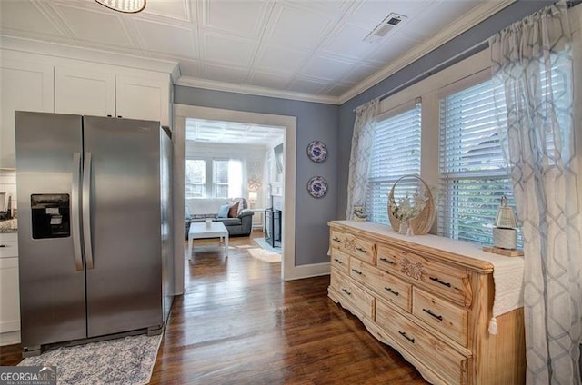 kitchen with crown molding, stainless steel refrigerator with ice dispenser, visible vents, dark wood-type flooring, and white cabinets