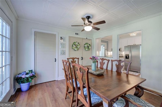 dining room with crown molding, wood finished floors, a ceiling fan, and baseboards