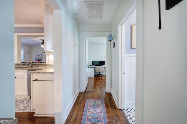 corridor with attic access, baseboards, dark wood-style flooring, crown molding, and a sink