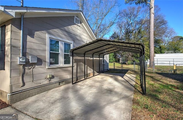 view of side of home featuring driveway, fence, and a detached carport