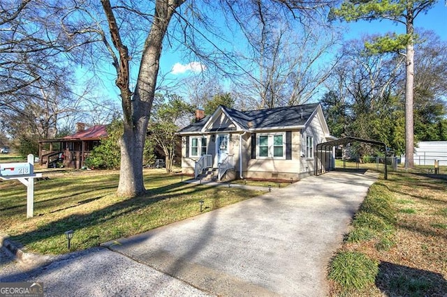 bungalow-style house featuring a carport, a front lawn, a chimney, and concrete driveway