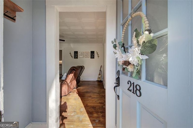 hallway with an ornate ceiling, crown molding, and wood finished floors