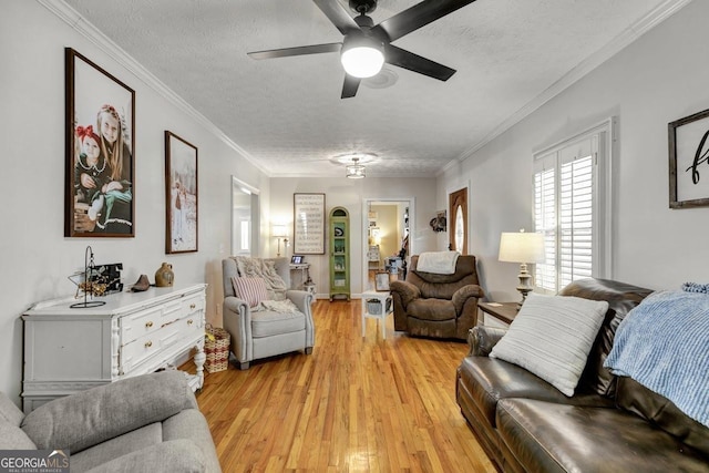 living room featuring light wood-style floors, crown molding, a textured ceiling, and a ceiling fan