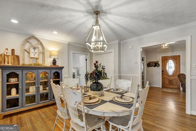 dining space featuring crown molding, a textured ceiling, a chandelier, and wood finished floors