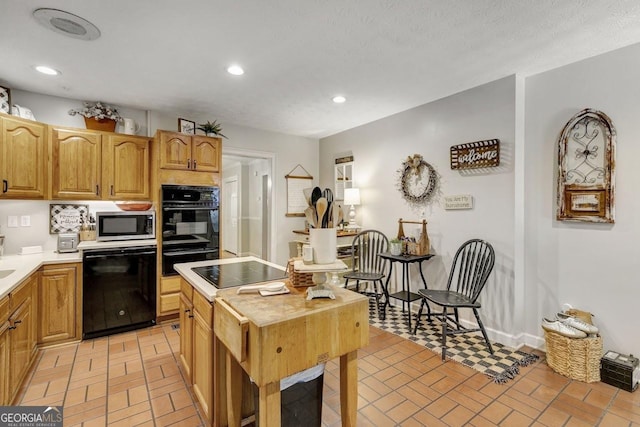 kitchen featuring black appliances, baseboards, brick floor, and recessed lighting