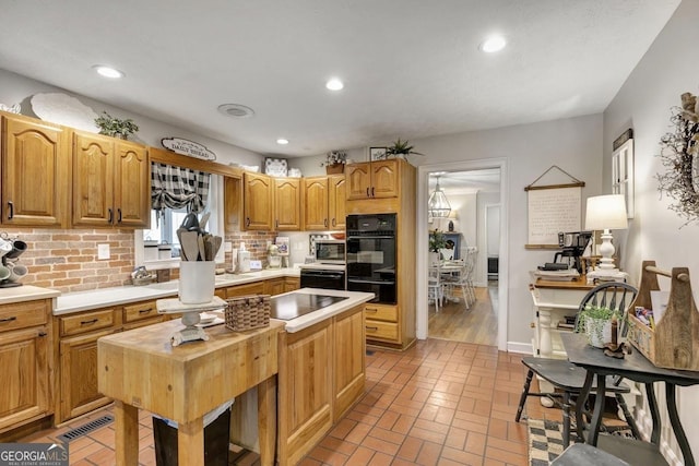 kitchen with visible vents, decorative backsplash, brick floor, black appliances, and recessed lighting